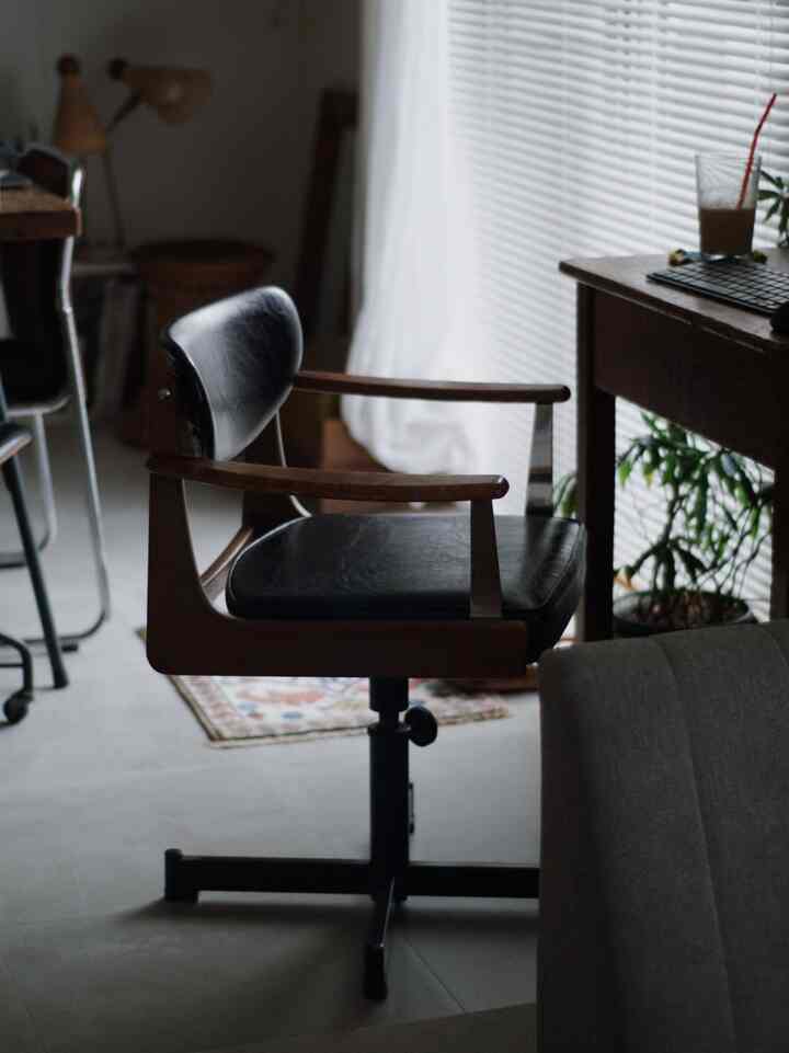 Natural-toned home office space featuring a black leather office chair and wooden desk, creating a calm atmosphere