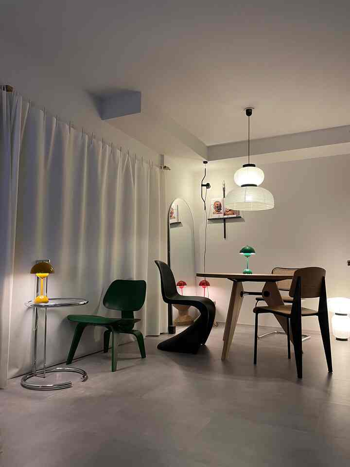 白と緑の色調のダイニングルーム、多様なデザインのダイニングチェアとペンダントライトが配置された印象的なモダンナチュラルな空間