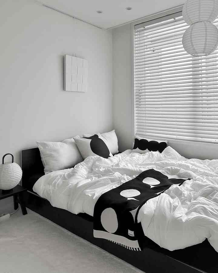 白と黒のモノトーンでまとめられた寝室。シンプルなベッドと枕、掛け布団カバーが落ち着いた雰囲気のインテリア
