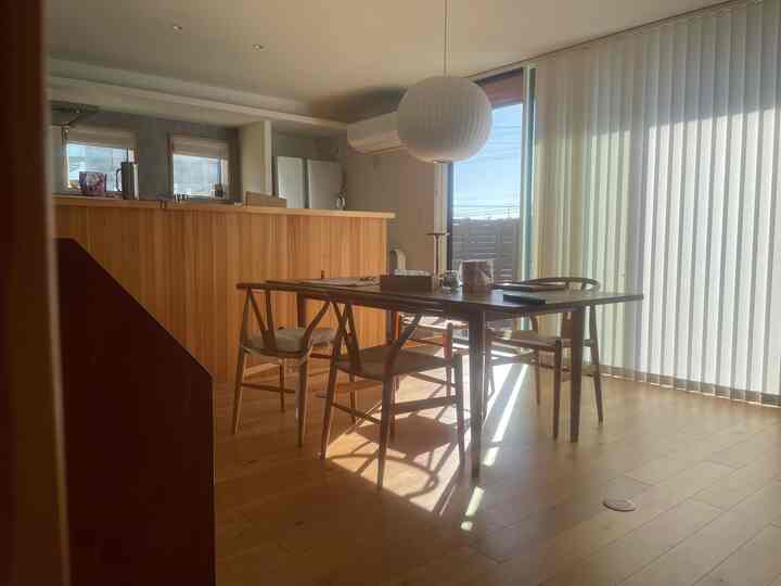 温かみのある木目調と白を基調としたダイニングルーム、バーチカルブラインドとバブルペンダントライトが配置された雰囲気のあるインテリア