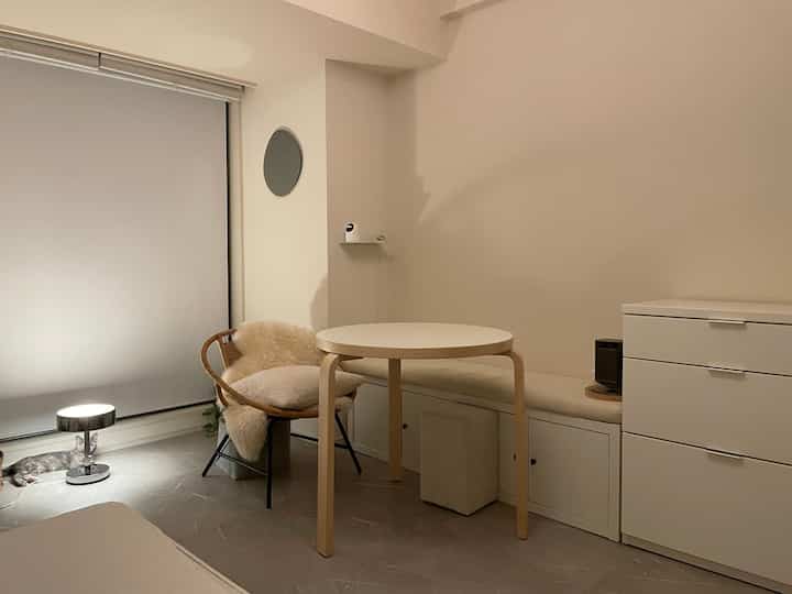 白と木目調の小さな部屋、丸テーブルと椅子が配置されたシンプルでナチュラルなカフェ風の雰囲気のあるインテリア