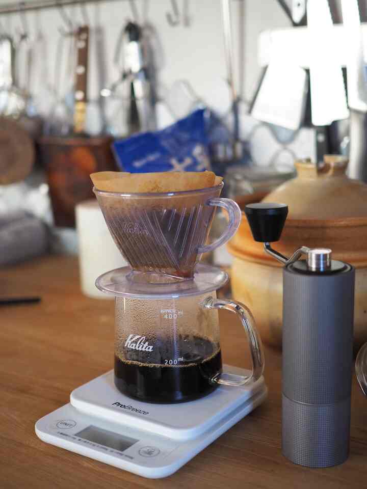 Bright-toned kitchen featuring transparent coffee server and grinder in a natural home cafe setting