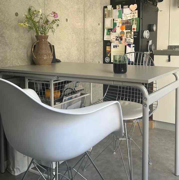 グレー調のダイニングルーム、グレーのダイニングテーブルにイームズアームチェアとワイヤーチェア、花瓶が配置された清潔感のある空間