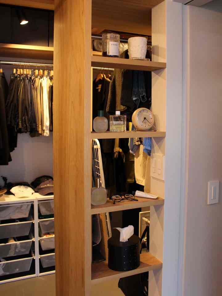 White-walled walk-in closet featuring wood tone shelves, organized clothes racks, and storage drawers for practical use