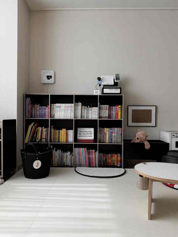 白い背景に黒い家具と子供用本棚が配置された赤ちゃんと暮らすリビングの雰囲気あるインテリア