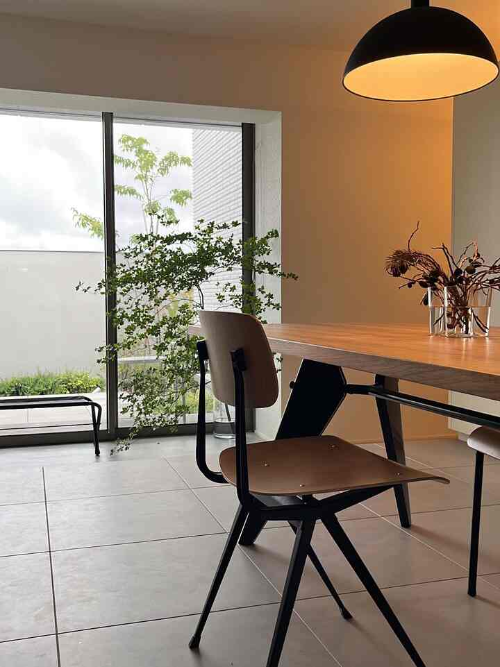 木目調と黒のペンダントライトが調和するモダンなダイニング、広い窓からバルコニーが見える清潔感のある空間