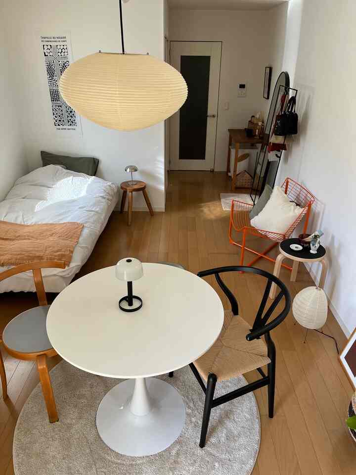 White and wood tone bedroom for single household featuring a central round table and pendant light in a natural, cozy atmosphere