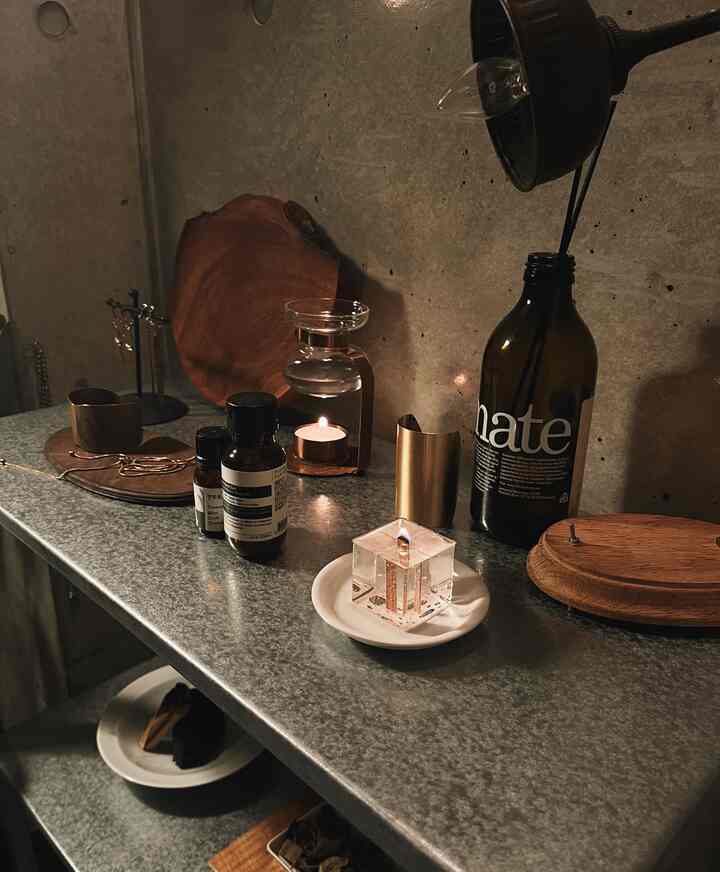 グレーの金属棚にキャンドルやディフューザー、木製トレイと小物が配置されたモダンでナチュラルな雰囲気の空間