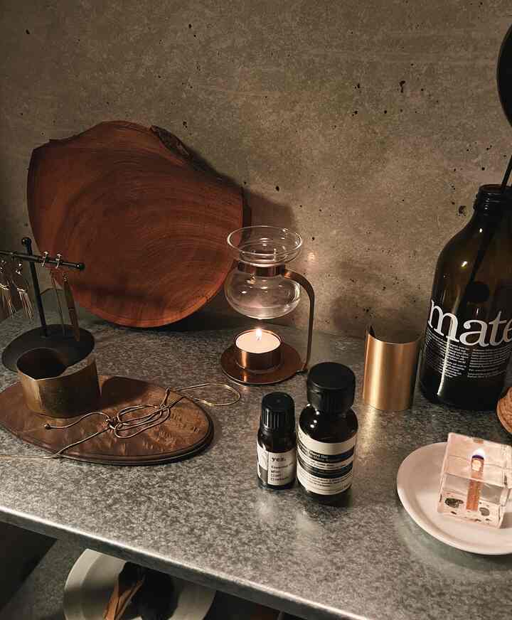 Cozy space featuring aroma oil warmer and candle on a brown wood and silver metal table