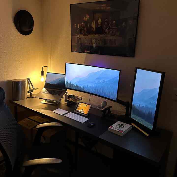 ダークトーンのホームオフィスワークスペース、3台のモニターと黒いデスク、オフィスチェアが配置されたモダンな空間