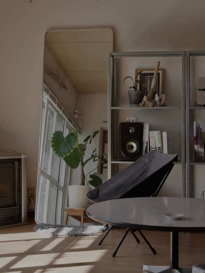 ホワイトとナチュラルカラーのリビング、アウトドアチェアと棚、植物が配された雰囲気のある空間