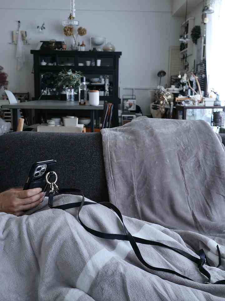 グレー調のリビング、ダークグレーのソファにブランケットが掛けられた、落ち着いた雰囲気のあるインテリア