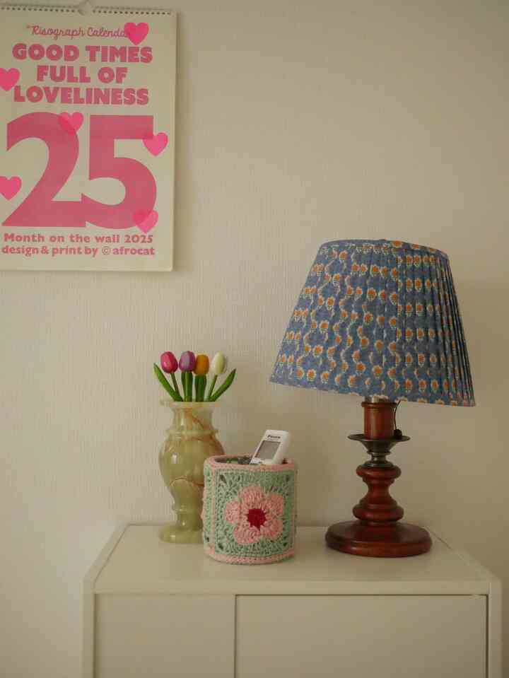 白い壁とキャビネットの上にヴィンテージ風のテーブルランプと花瓶が置かれたシンプルな寝室のインテリア