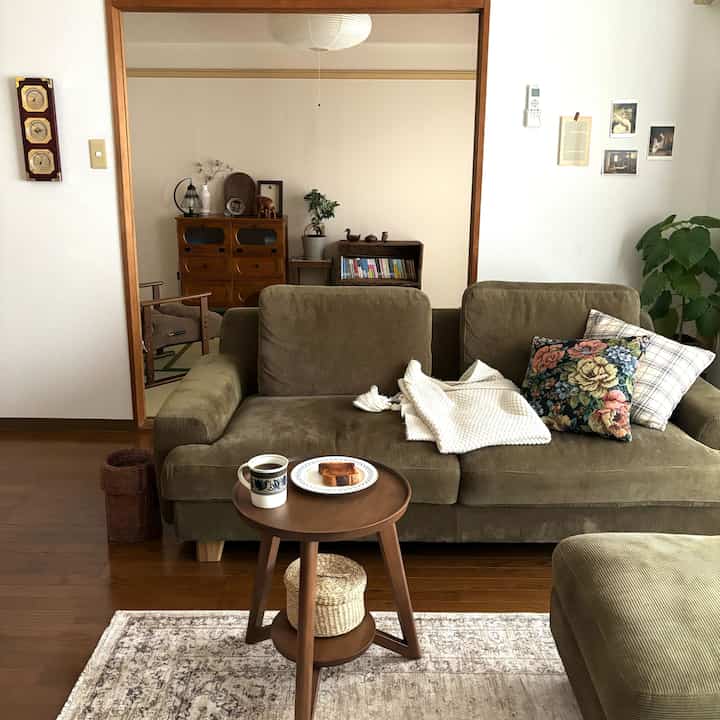緑色のコーデュロイソファと木目調の家具が配置された落ち着いた雰囲気のヴィンテージリビング