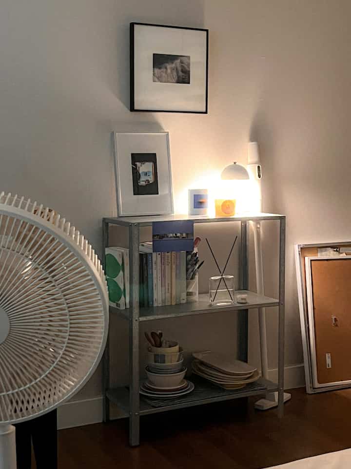 柔らかい照明とメタル棚、木目調の床がある落ち着いた寝室のインテリア