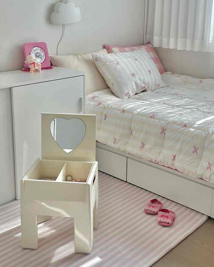 ピンクとホワイトの子供部屋、化粧台兼収納スツールとベッドが整然と配置された可愛らしい空間