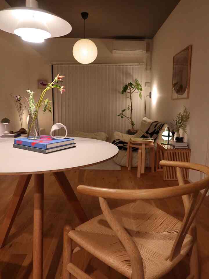 温かみのあるウッドトーンとホワイトを基調とした北欧スタイルのリビング、アルテックのスツールとアームチェアが配置された雰囲気のある空間