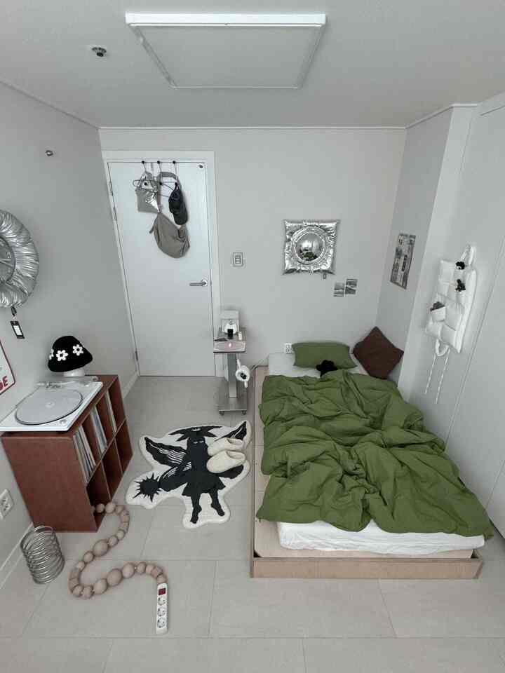 White and green toned compact single bedroom featuring a single bed and simple furniture in a minimal modern style