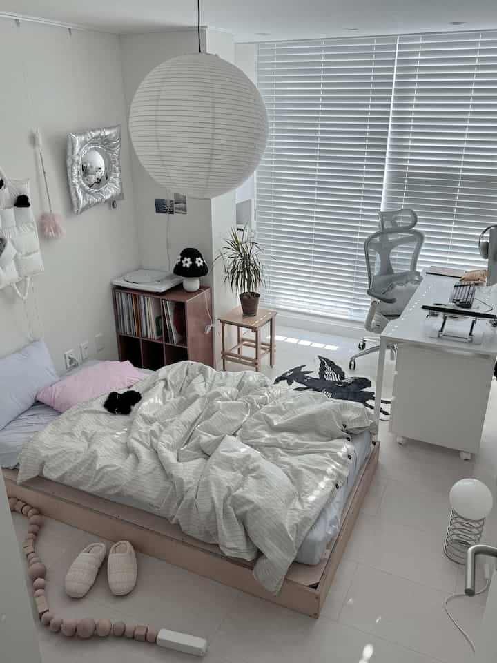 White-toned bedroom featuring wooden furniture and desk with a minimal, natural atmosphere