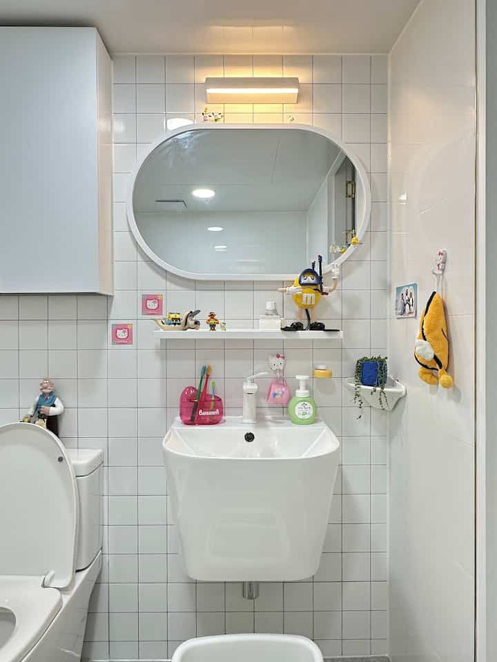Bright and clean white tiled modern living room restroom featuring a sink with decorative shelves