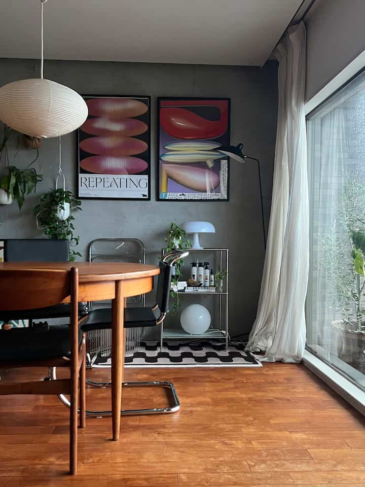 グレー調のリビング兼ダイニングルーム、ウッドトーンのテーブルと黒い椅子が配置されたモダンで温かみのある空間