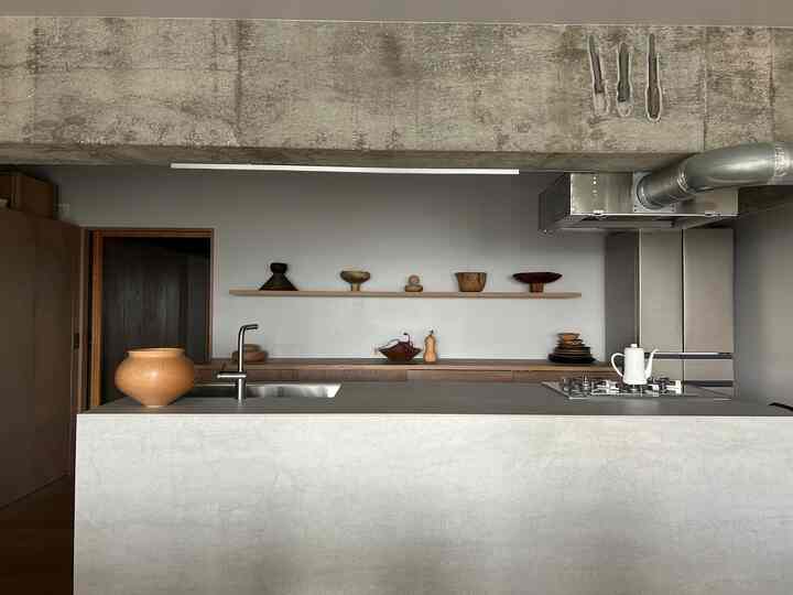 ナチュラルな木目調とグレーのコンクリートが調和したモダンなキッチンカウンターの印象的な空間