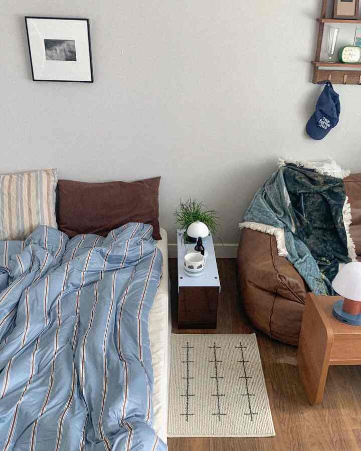 ナチュラルと木目調が調和した寝室、ブルーストライプの寝具とブラウンのビーズクッションがあるシンプルな空間