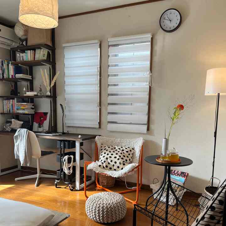 Natural-toned living and home office space with wooden floor, featuring an orange armchair, desk, and white furniture creating a cozy atmosphere
