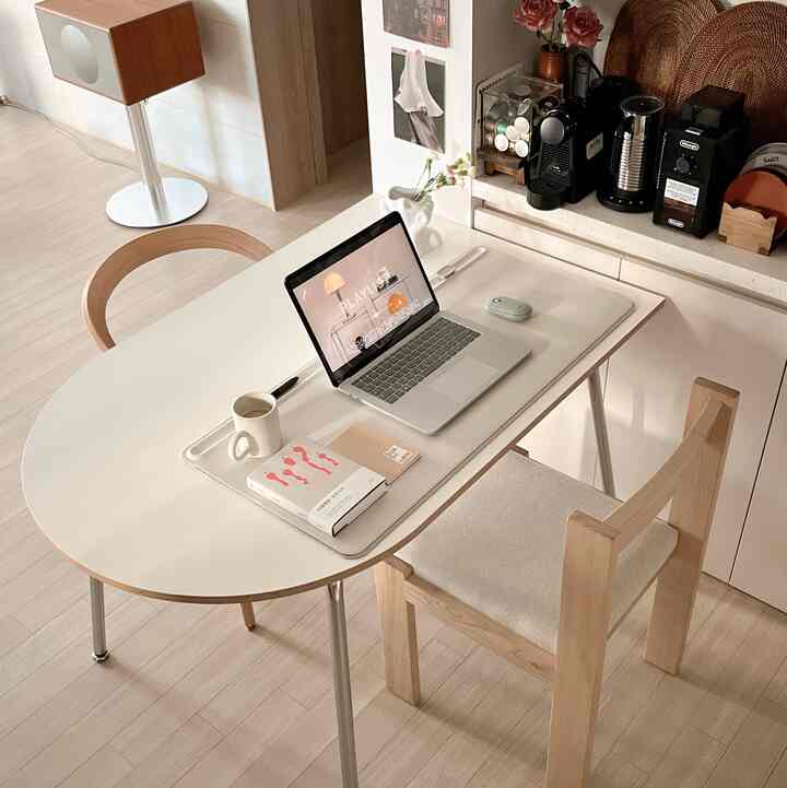 Cozy kitchen home cafe space featuring a white semi-oval table with steel legs and wood tone chairs