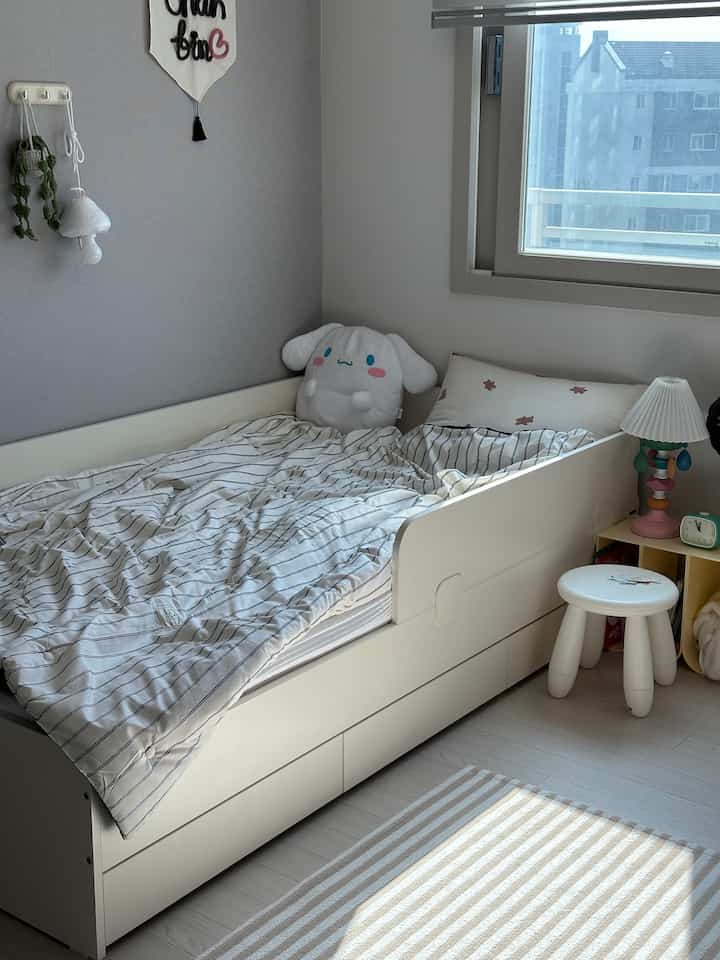 白とナチュラルカラーの子供部屋、収納付きベッドと可愛らしい小物が配置された雰囲気のあるインテリア