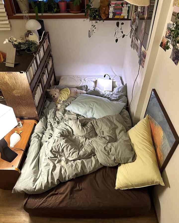 ナチュラルな木目調とグレーの寝具が配置された寝室、犬と一緒にくつろぎながら読書を楽しむ雰囲気のあるインテリア