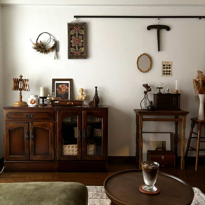 濃いブラウンの木目調ヴィンテージリビング、アンティーク家具とポスターが配された雰囲気のある空間