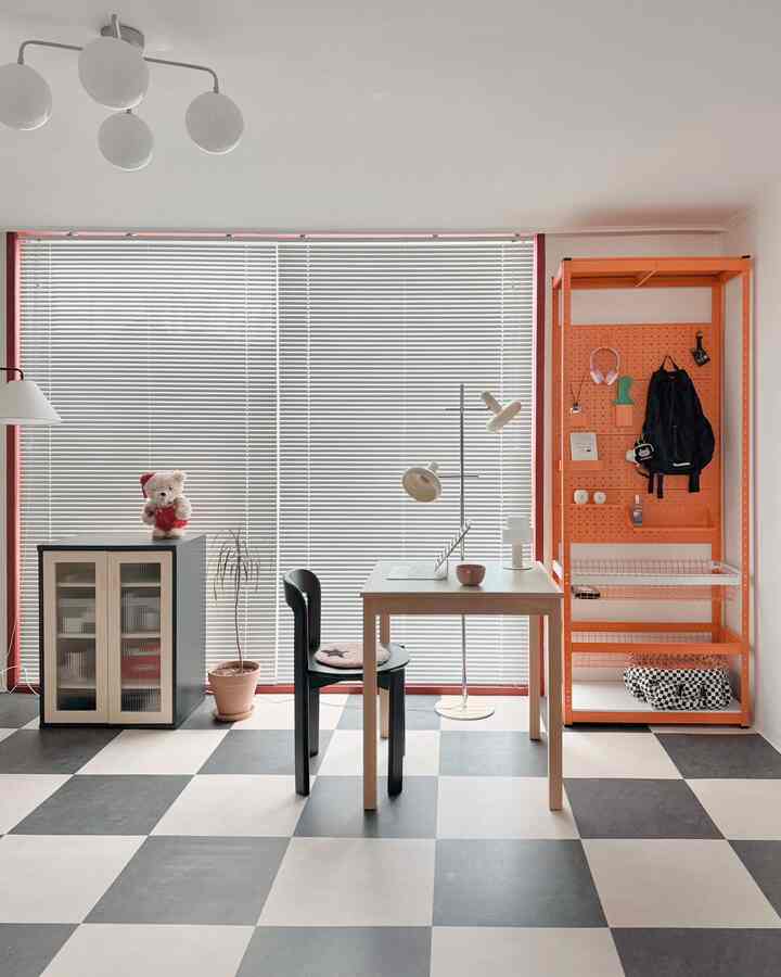 白黒のチェック柄デコタイルの床とオレンジ色の棚が配置されたリビング風の勉強部屋