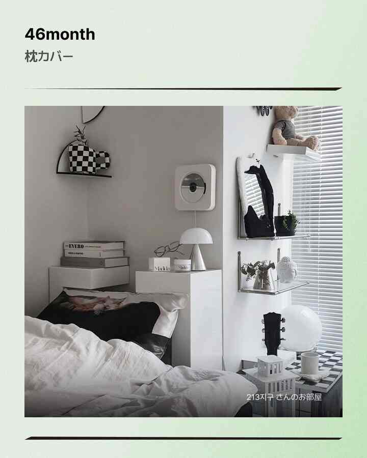 白と黒のモノトーンベッドルーム、猫の枕カバーとシンプルな棚が配された落ち着いた雰囲気のインテリア