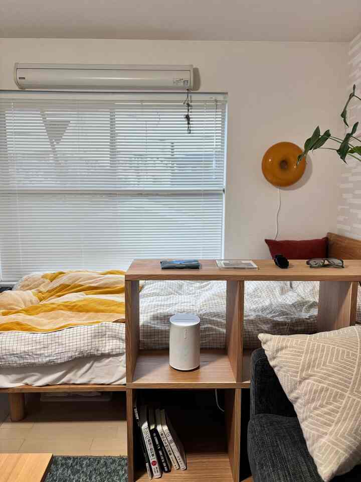 Natural-toned 1K studio featuring Muji shelves and a Sonos smart speaker in a cozy setting