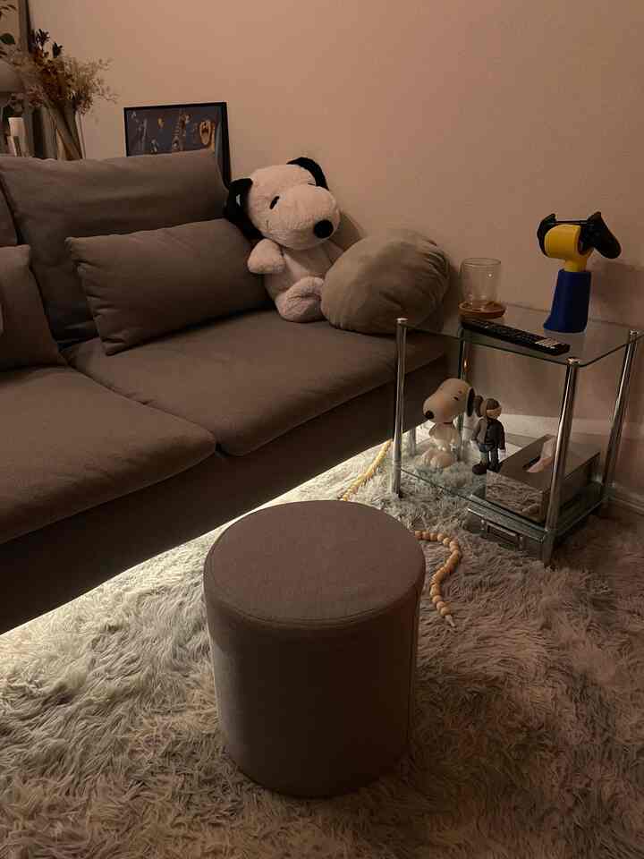 落ち着いたグレーの色調の一人暮らしリビング、ソファとサイドテーブル、間接照明が配置された雰囲気のある空間