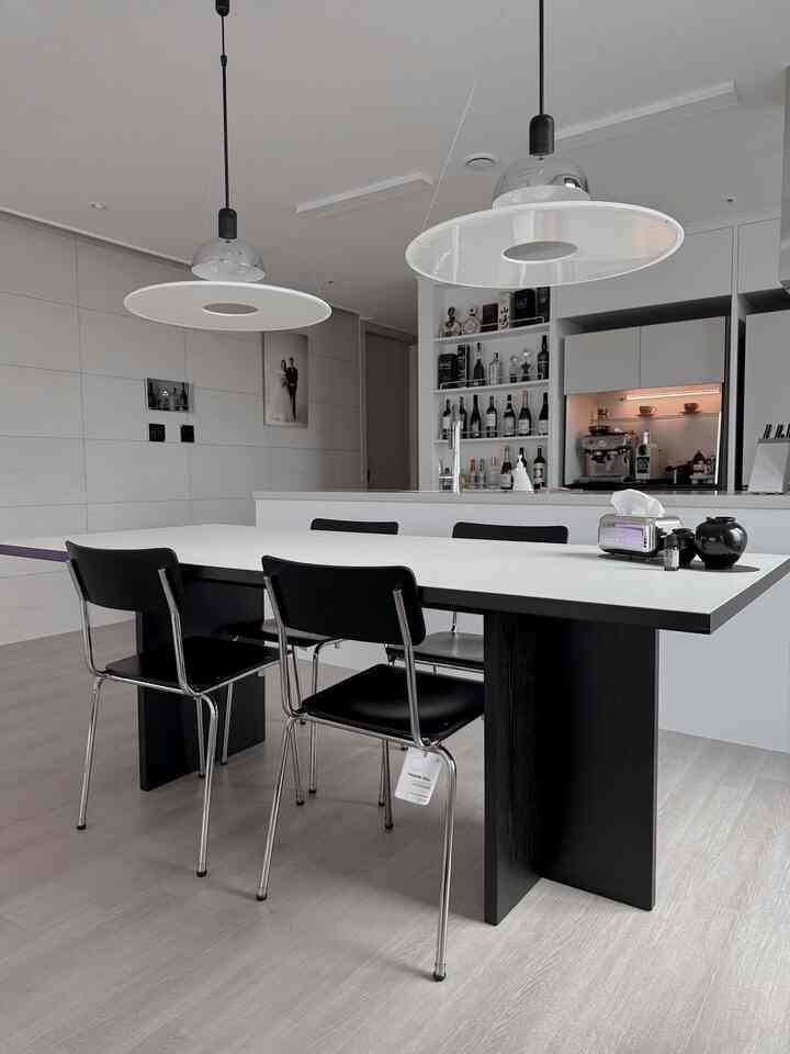 White and black toned dining room featuring an 8-person dining table and pendant lights in a modern kitchen space