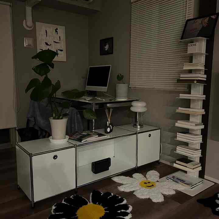 ナチュラルカラーのモダンなホームオフィス、白いキャビネットとデスク、植物、印象的な縦型本棚が配置された落ち着いた空間