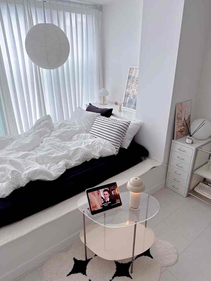 White-toned bedroom featuring black mattress, white duvet cover, and striped pillow in a clean modern setting