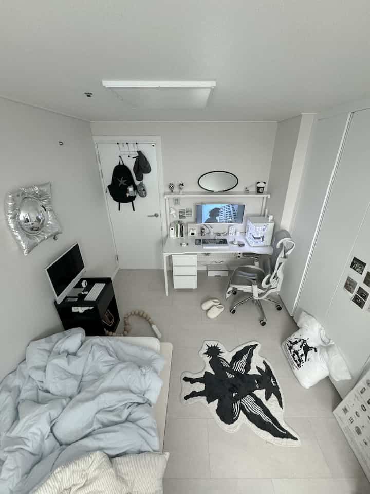 Monotone white and gray compact bedroom featuring a tidy desk setup and bedding with a clean, minimal aesthetic