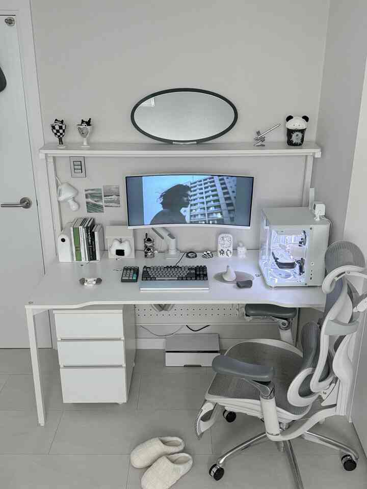White-toned home office space featuring a tidy desk, ergonomic office chair, and curved monitor in a modern setup