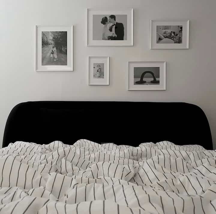 モノトーンでシンプルなスタイルの寝室、黒いベッドフレームとストライプの寝具が配置された落ち着いた空間