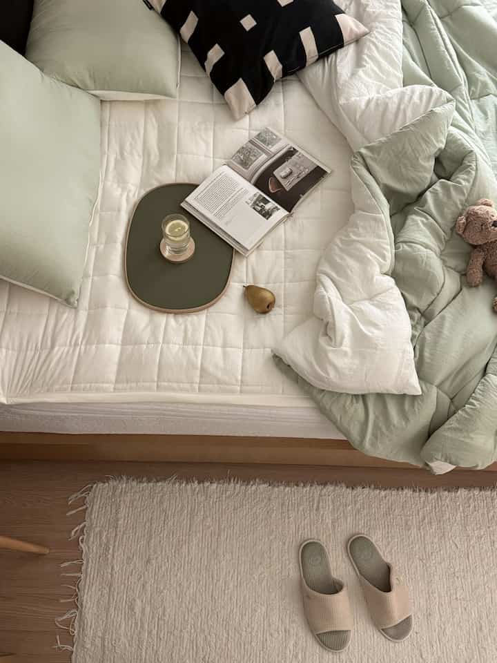 ベージュとホワイト、淡いグリーンの寝室、ふかふかの寝具とスリッパが配置された落ち着きのあるインテリア