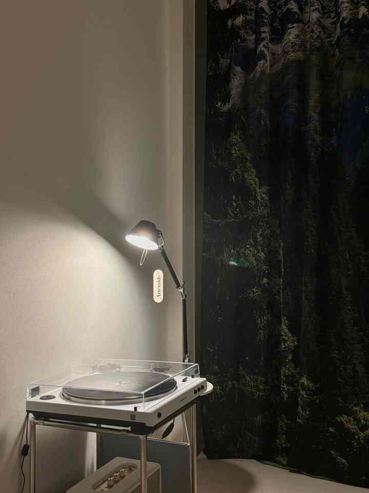 White and black tone space featuring a white wireless turntable and lit black table lamp, creating a sleek atmosphere