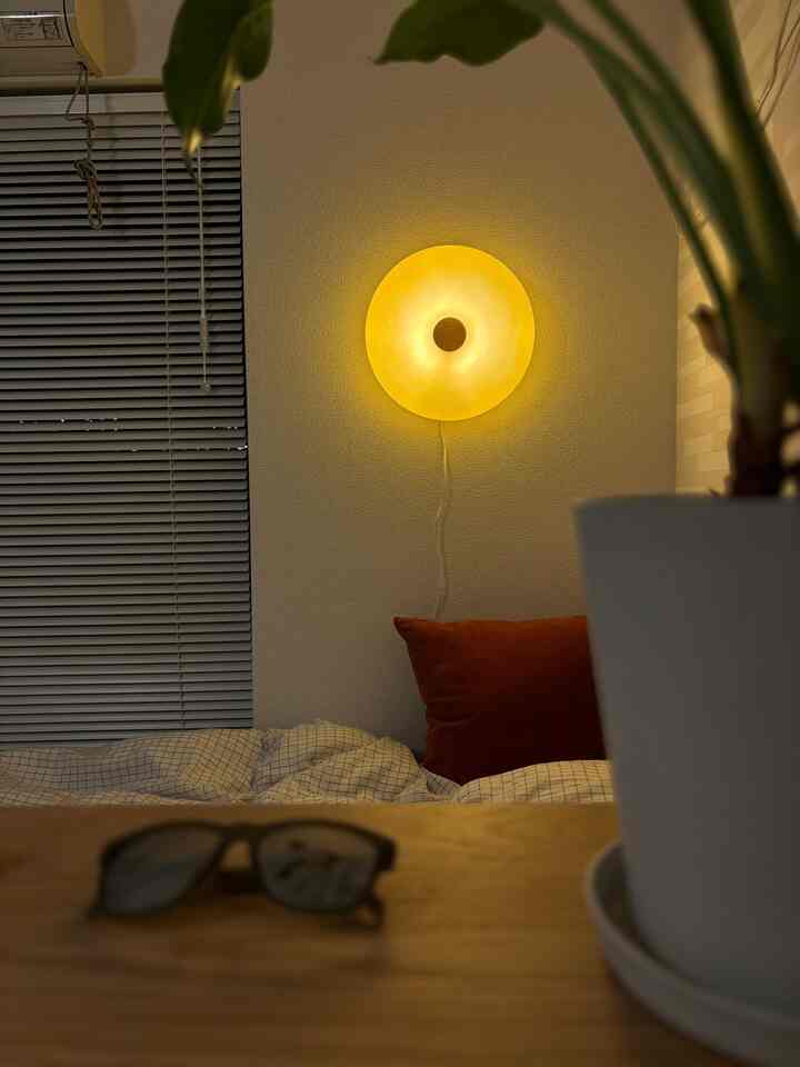 Natural wood-tone bedroom illuminated by warm yellow mood lighting, featuring checkered bedding and cushions in a cozy single household 1K room