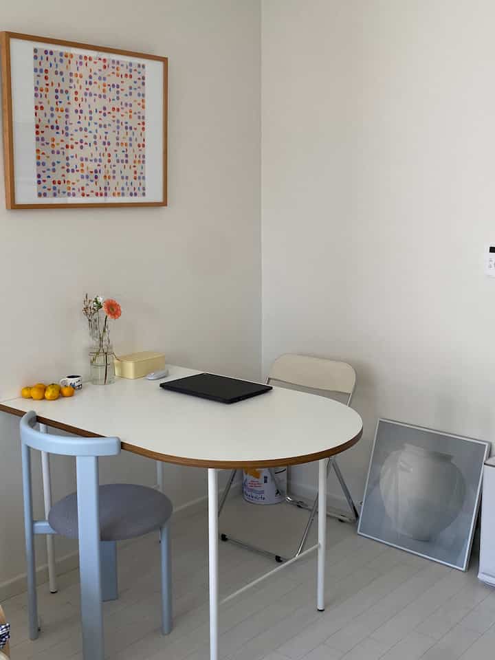 Minimal small dining room in white tones featuring two-person dining table and chairs with clean decor