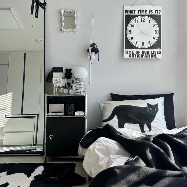 Black and white bedroom space featuring a cat pillow cover and nightstand, showcasing a simple modern design