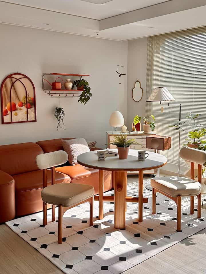 Warm natural-toned living room featuring a round ceramic table and beige dining chairs in a cozy setting