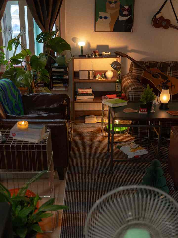 暖かい照明と植物が配されたリビング、レザーとチェック柄のソファが置かれた居心地の良い空間