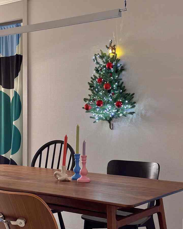 ホワイトの壁と木目調のダイニングテーブルがあるダイニングルーム、クリスマスの飾りとカラフルなキャンドルが配置された雰囲気のある空間